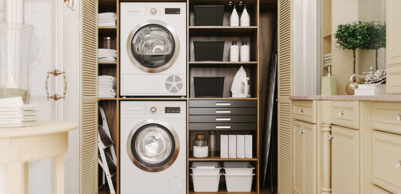 Organized laundry room with cream cabinets, neat shelves and double stack washing machine and dryer