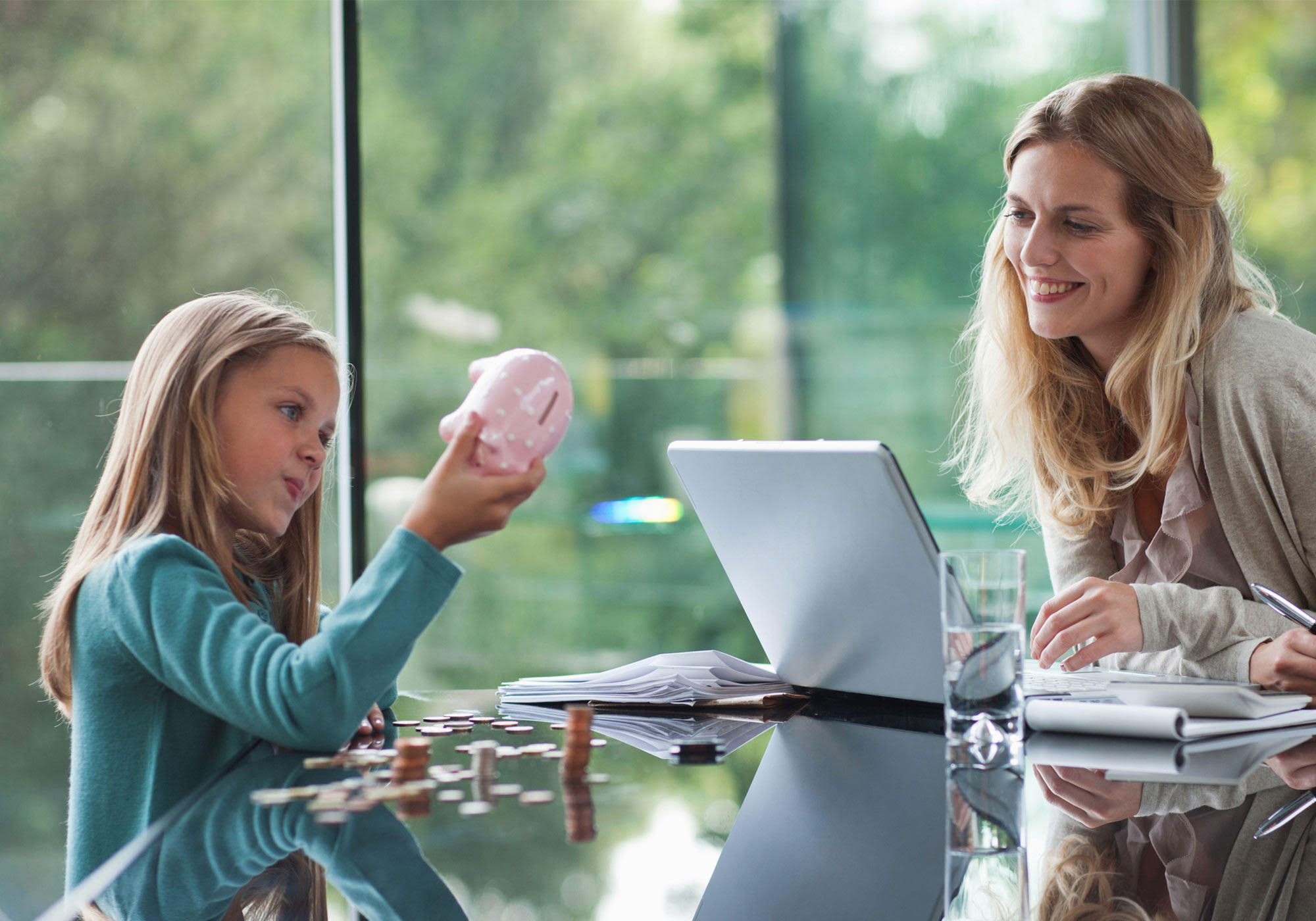 Mom with daughter looking in piggy bank