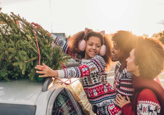 family putting christmas tree on their vehicle