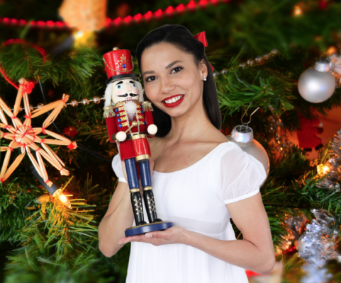 Ballet dancer holding Nutcracker near Christmas tree