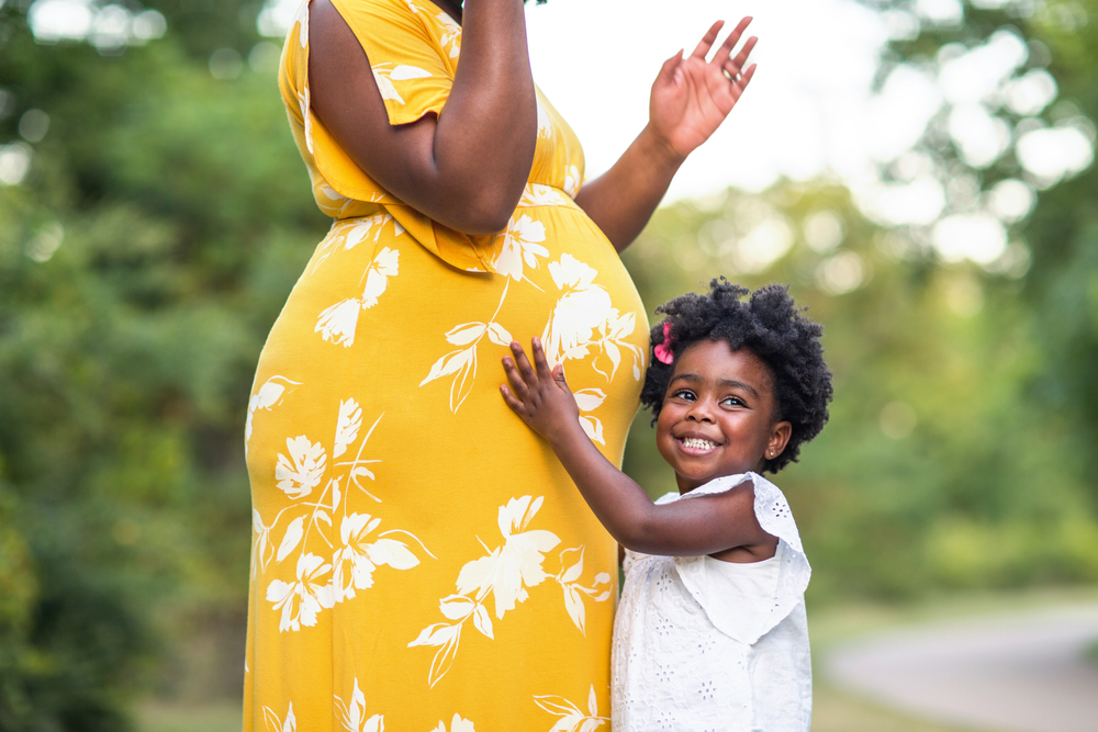 pregnant mother with young daughter touching belly
