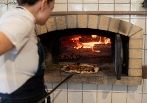 Pippin Hill chef placing pizza in stone fire oven