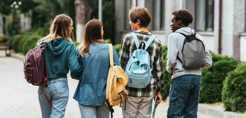 group of teenagers with backpacks walking away