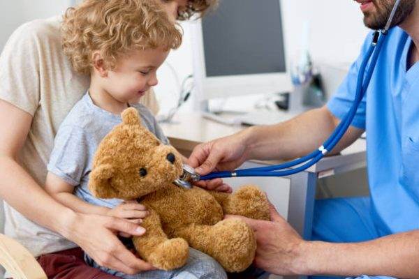 Child sits with teddy bear at the doctors office