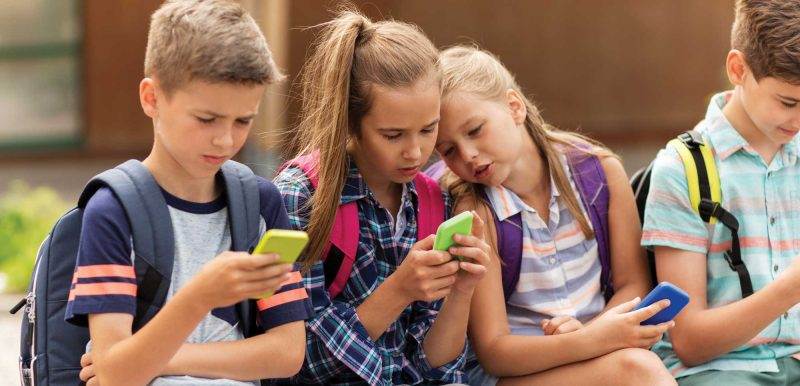 school children looking at their cellphones