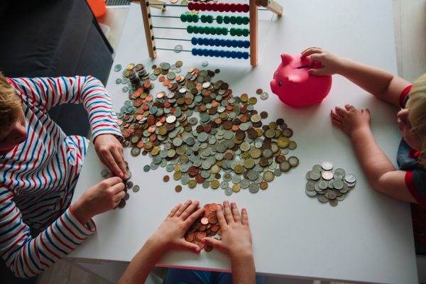 kids count money, boy and girls put coins into piggy bank, money saving concept