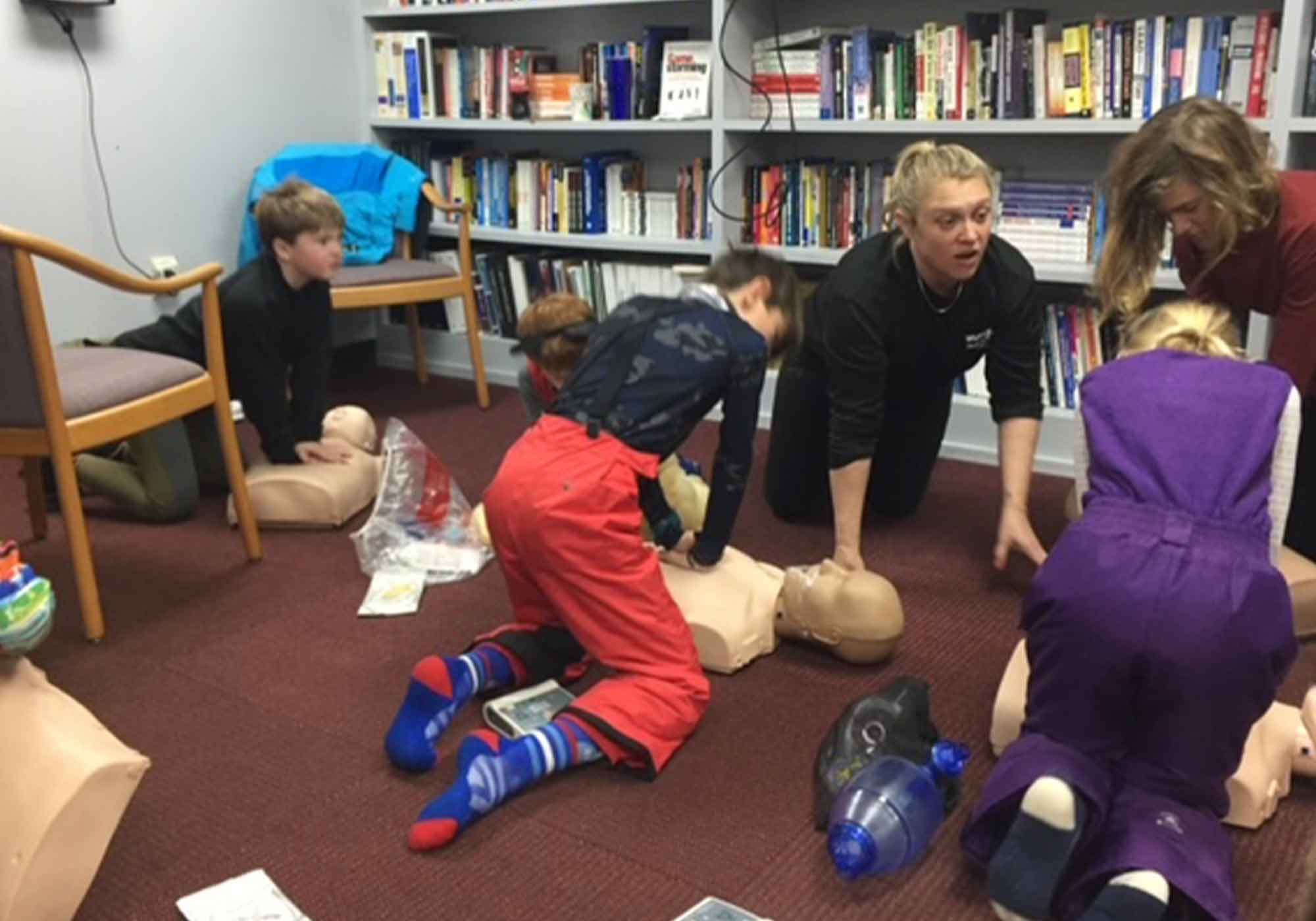 Youth working on CPR dummy for youth ski parol training