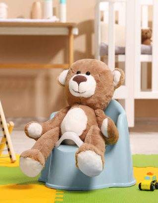 Cute teddy bear on light blue baby potty in room. Toilet training