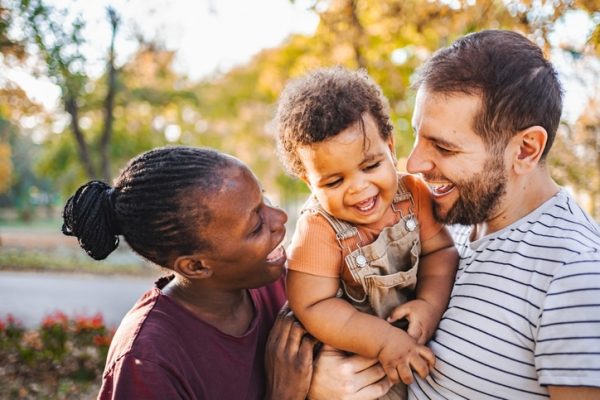 parents laugh with toddler son in arms