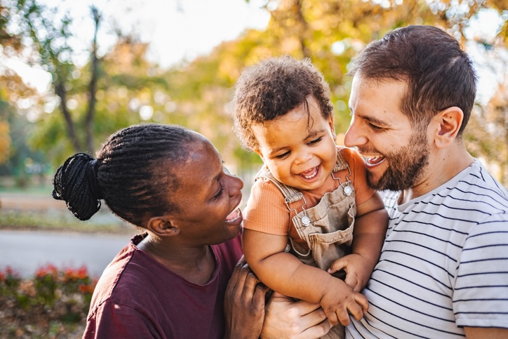 parents laugh with toddler son in arms
