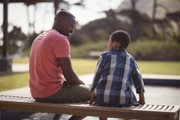 Smiling father talking to son outside