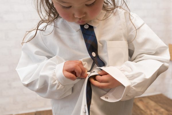 Little girl buttoning shirt
