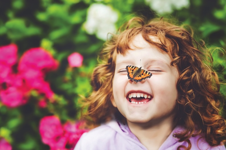 Laughing girl with a butterfly on her nose