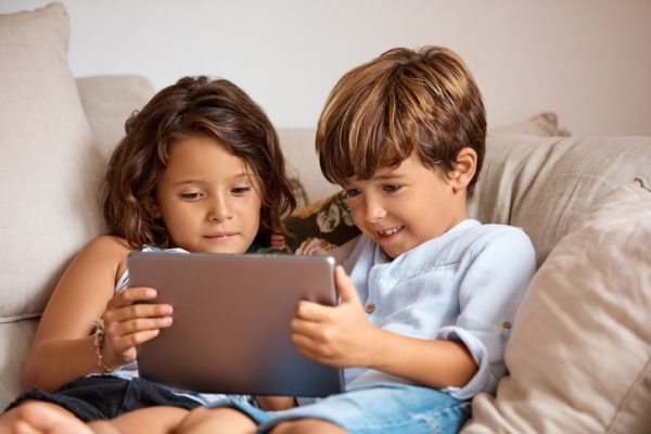 little girl and boy sharing a digital tablet at home