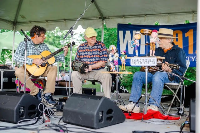Three men sitting on stage playing music