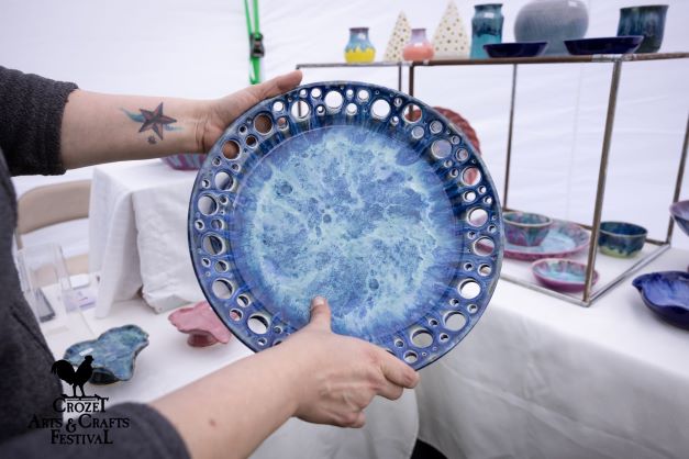 Hands holding blue ceramic plate with circles cut out of rim